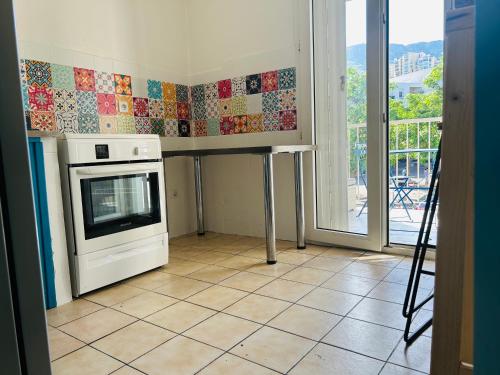 une cuisine avec une cuisinière et un micro-ondes dans l'établissement 1 chambre dans appartement 2 chambres proche mer, centre-ville et commerces, à Bastia