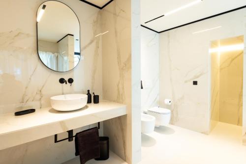 a bathroom with a sink and a mirror and a toilet at Extreme Luxury Villa in Punta Ala with Private Pool, SPA and Gym in Punta Ala