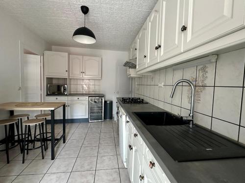 - une cuisine avec des placards blancs, un évier et une table dans l'établissement Spacieux T3 avec vue imprenable, au Puy-en-Velay