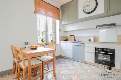 une cuisine avec une table, des chaises et une horloge dans l'établissement Le Nordet Vert, à Albi