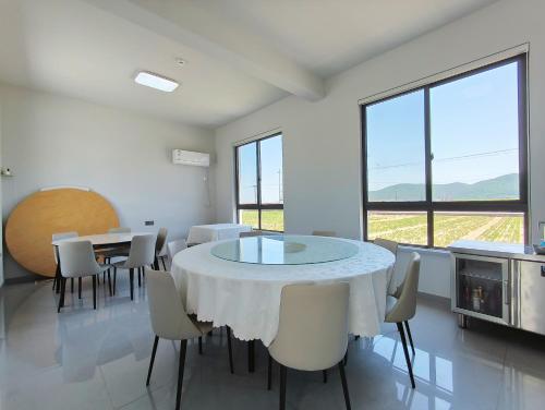 a dining room with a table and chairs and windows at Daishan Mountain and Sea Cloud Homestay Sunrise Seaview Bed and Breakfast in Zhoushan