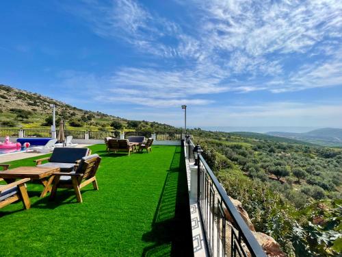 a balcony with chairs and tables on the grass at אוצר הטבע in Maghār