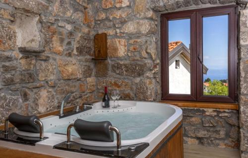 a stone bathroom with a bath tub with a window at Casa Antica - Storia Verde Opatija in Veprinac