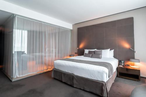 a bedroom with a large bed and a large window at The Canvas Dubai - MGallery Hotel Collection in Dubai