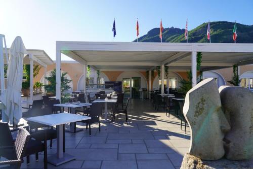 an outdoor patio with tables and chairs and flags at Hotel Parco Delle Agavi in Ischia