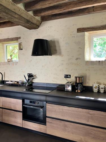 a kitchen with a stove and a counter top at Maison de vacances avec piscine chauffée, jacuzzi et jardin privé - proche circuit des 24h du Mans in Saint-Christophe-en-Champagne