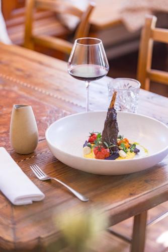 a plate of food and a glass of wine on a table at Der Schlosswirt zu Anif - Biedermeierhotel und Restaurant in Anif