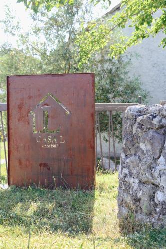 a metal sign sitting in the grass next to a rock at Casa L in Ulcinj