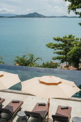 a view of the water from a resort with tables and umbrellas at The Kala in Amphoe Koh Samui