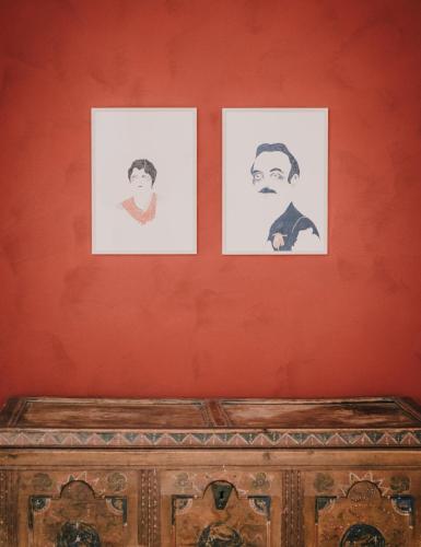 three framed portraits of a man on a red wall at Hotel & Gasthof zum Hirschen in San Genesio Atesino