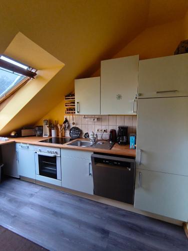 a kitchen with white cabinets and a sink and a stove at Gemütliche, ruhige Dachwohnung in Lütow für bis zu 4 Personen in Lütow