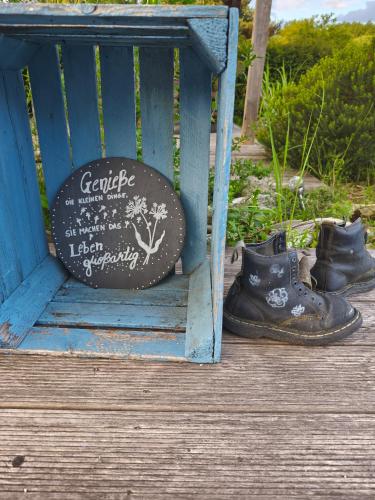 a sign sitting on a blue bench next to a pair of boots at Gemütliche, ruhige Dachwohnung in Lütow für bis zu 4 Personen in Lütow