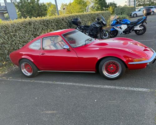 a red car parked in a parking lot with motorcycles at Hôtel Inn Design Resto Novo Le Mans in Arnage