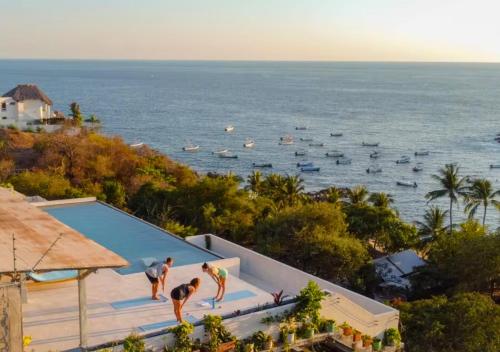 a group of people standing around a swimming pool near the ocean at Casa Cascada - Adults Only in Puerto Escondido