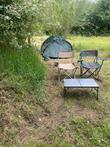 deux chaises et une table devant une tente dans l'établissement Les Sources Camping club, à Les Cresnays