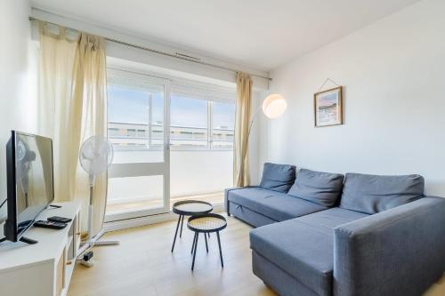 un salon avec un canapé bleu et une grande fenêtre dans l'établissement L'Océanide - Vue mer - Parking, à Saint-Hilaire-de-Riez