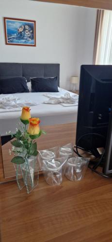 a room with a bed and a television and a vase with flowers at Hotel Viktorija in Seget Vranjica