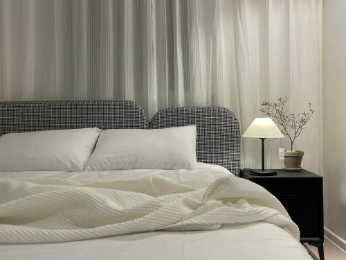 a bed with white sheets and a table with a lamp at Harangae in Seoul