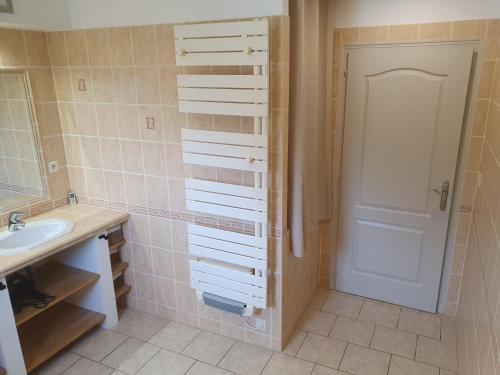 a bathroom with a sink and a mirror and a door at Gîte des Falaises 10 à 12 personnes in Souspierre
