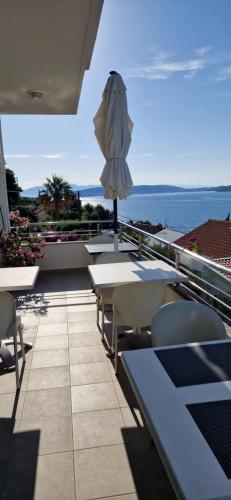 a patio with tables and chairs and an umbrella at Hotel Viktorija in Seget Vranjica