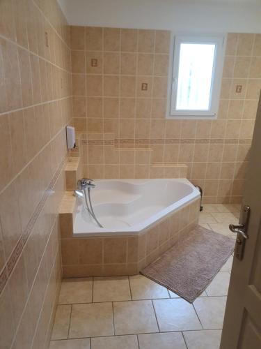 a bath tub in a tiled bathroom with a window at Gîte des Falaises 10 à 12 personnes in Souspierre