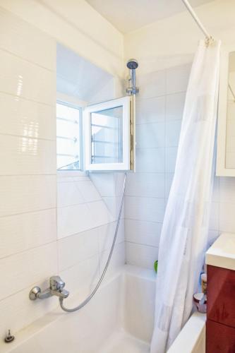 La salle de bains est pourvue d'une baignoire blanche avec rideau de douche. dans l'établissement Coeur de Paris sous les toits, à Paris