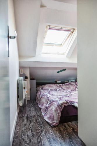 - une chambre mansardée avec un lit et une lucarne dans l'établissement Coeur de Paris sous les toits, à Paris