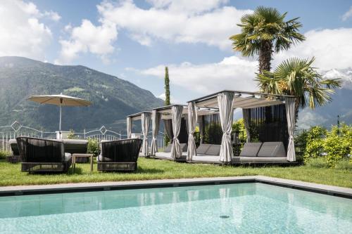 a resort with a swimming pool and chairs and a mountain at Small & Beautiful Hotel Gnaid in Tirolo