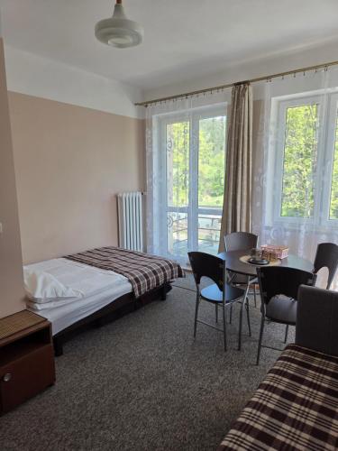 a hotel room with a bed and a table and chairs at WILLA "SZCZĘSNA" in Piwniczna