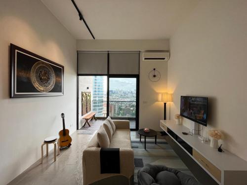 sala de estar con sofá y guitarra en The Establishment - Menara Teguh Bangsar, en Kuala Lumpur