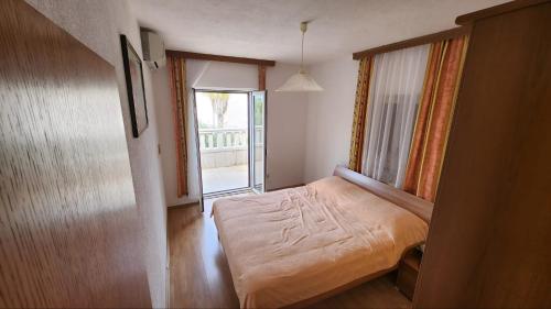 a small bedroom with a bed and a window at Apartments Jela in Splitska