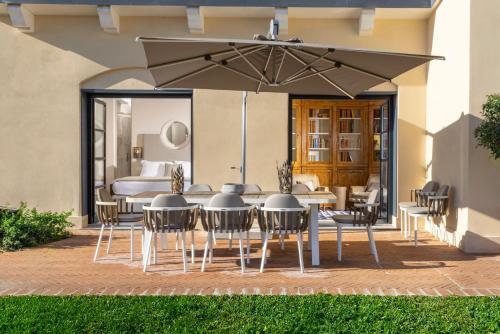 a patio with a table and chairs under an umbrella at Exclusive Home with pool and iconic View on Saint Peter in Rome
