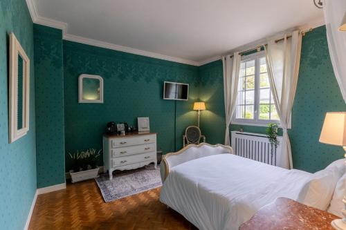 a bedroom with green walls and a bed and a window at Le Manoir 1977 in Jaunay-Marigny