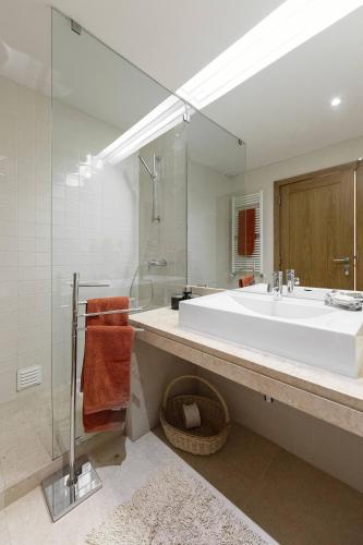 a bathroom with a large white sink and a shower at Oasis Pool Villa - Praia D'El Rey Golf Resort in Palaios