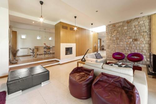 a living room with a white couch and a brick wall at Oasis Pool Villa - Praia D'El Rey Golf Resort in Palaios