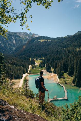 a man with a backpack standing on a hill overlooking a lake at Manali Lodge by Alpine Resorts in Courchevel
