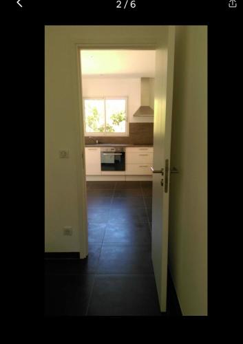 une porte ouverte menant à une cuisine avec une fenêtre dans l'établissement Charmant logement, à Pianottoli-Caldarello