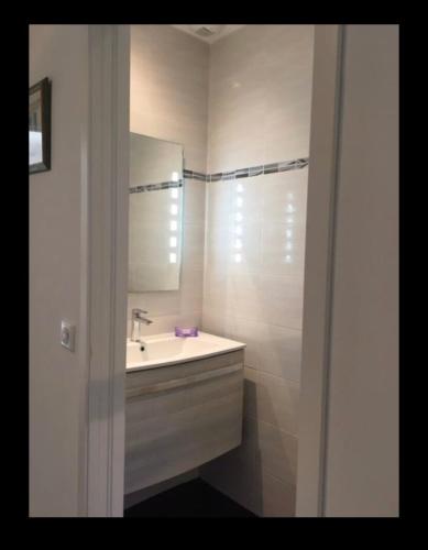 une salle de bain blanche avec un lavabo et un miroir dans l'établissement Charmant logement, à Pianottoli-Caldarello