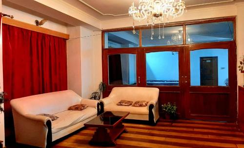 a living room with two chairs and a chandelier at him holidays inn shimla in Shimla