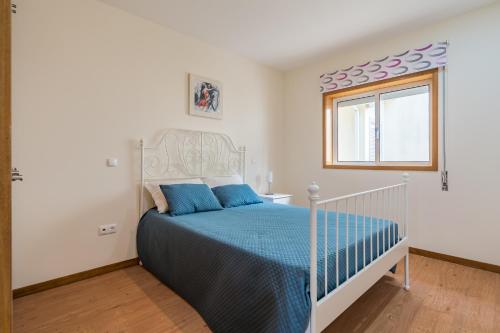 ein Schlafzimmer mit einem Bett mit blauen Laken und einem Fenster in der Unterkunft Casal do Porto - Um refugio de férias in Vila Verde
