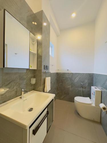 a bathroom with a sink and a toilet and a mirror at Neo Bay Hotel in Weligama