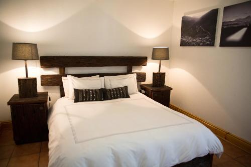 a bedroom with a large white bed with two lamps at Karoo Khaya in Prince Albert