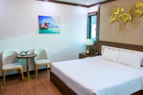 a bedroom with a bed and a table and chairs at New Sun Móng Cái Hotel in Móng Cái