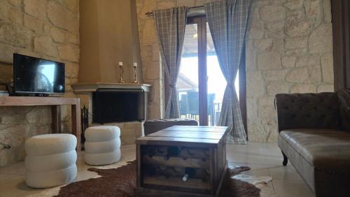 a living room with a couch and a tv at To Petrino, Stylish Stone House, Elani in Siviri