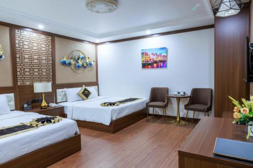 a hotel room with two beds and a desk at New Sun Móng Cái Hotel in Móng Cái