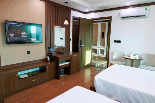 a hotel room with a bed and a flat screen tv at New Sun Móng Cái Hotel in Móng Cái