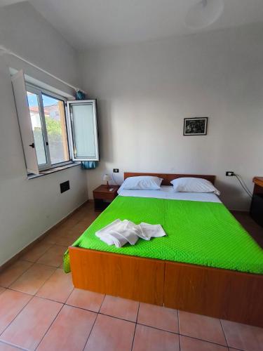 a bedroom with a green bed with two towels on it at Anthos Residence sul mare in Cariati
