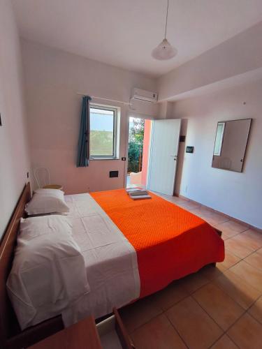 a bedroom with a large bed with an orange blanket at Anthos Residence sul mare in Cariati