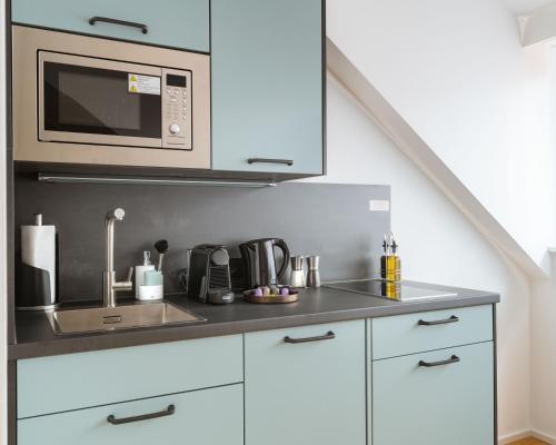 a kitchen with a sink and a microwave at Limehome Graz Trauttmansdorffgasse in Graz