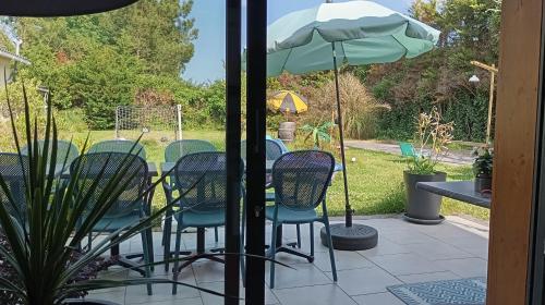 un patio avec des chaises et une table avec un parasol dans l'établissement Entre Bassin et lacs, à Gujan-Mestras